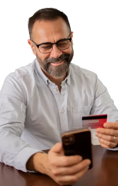 "Imagen de un hombre sosteniendo un teléfono móvil en una mano y una tarjeta de crédito en la otra